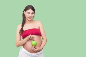 jovem grávida mulher detém uma verde maçã foto