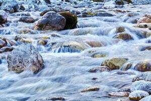 rochoso riffle em uma Claro montanha rio fechar-se, a água é borrado dentro movimento foto