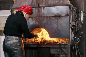 mulher ferreiro perto uma flamejante forja forno foto