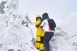 homem e mulher Viajantes descer a partir de a Nevado topo do a montanha foto