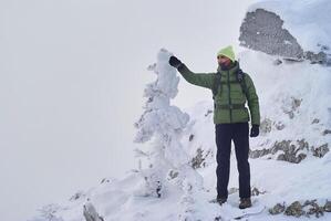 caminhante com uma walkie-talkie pares para dentro a distância, em pé em topo do uma montanha durante uma tempestade de neve foto