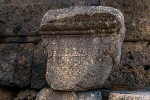 meio apagado Antiguidade inscrição em uma peça do pedra entre a ruínas do a antigo cidade do faselis, Peru foto