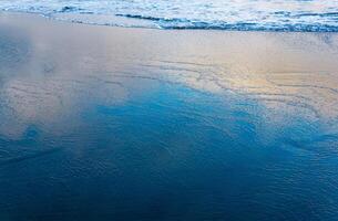 oceano de praia com uma onda chegando voltar, dentro que a céu é refletido foto