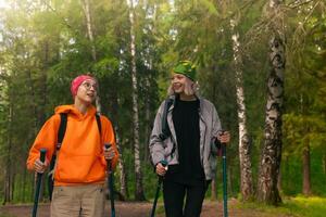 dois Adolescência meninas estão caminhada dentro a floresta com nórdico caminhando postes foto