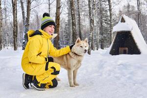 mulher acariciando uma rouco cachorro dentro a inverno floresta foto