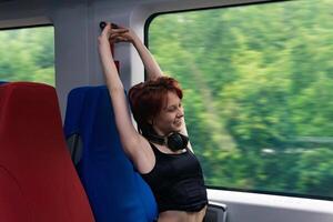 menina dentro uma passageiro trem transporte é alongamento, cansado a partir de uma grandes passeio foto