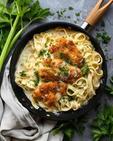 ai gerado crocantes frango fettuccine Alfredo em a Preto frigideira, lá estão salsão folhas e pano por aí a panela foto