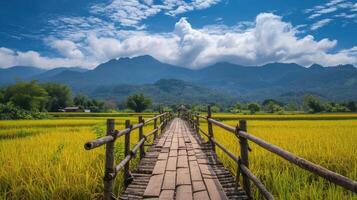 ai gerado de madeira ponte alongar através a amarelo arroz Campos com montanhas nuvens e azul céu dentro fundo foto