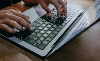 o negócio homem trabalhando com computador portátil. homem mãos digitando em computador portátil teclado. Gerente trabalhos processo. computador portátil em de madeira mesa. social rede, planejamento, comunicação. foto