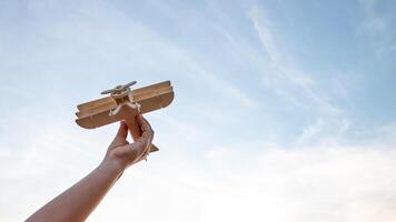 criança segurando uma de madeira avião modelo Alto dentro a céu foto