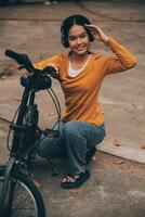 feliz jovem ásia mulher enquanto equitação uma bicicleta dentro uma cidade parque. ela sorriu usando a bicicleta do transporte. ambientalmente amigáveis conceito. foto