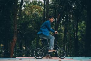 jovem bonito barbudo homem levando uma pausa enquanto viajando a cidade com dele bicicleta usando dele digital tábua olhando longe pensativamente foto