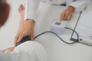 masculino médico usa uma sangue pressão monitor para Verifica a corpo pressão e pulso do a pacientes quem venha para a hospital para exames, médico tratamento e saúde Cuidado conceito. foto
