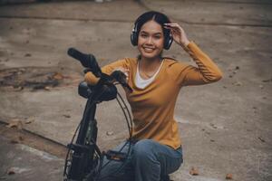 feliz jovem ásia mulher enquanto equitação uma bicicleta dentro uma cidade parque. ela sorriu usando a bicicleta do transporte. ambientalmente amigáveis conceito. foto