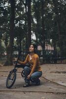 feliz jovem ásia mulher enquanto equitação uma bicicleta dentro uma cidade parque. ela sorriu usando a bicicleta do transporte. ambientalmente amigáveis conceito. foto