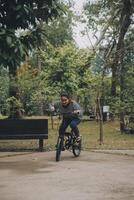 feliz ásia jovem mulher andar e passeio bicicleta dentro parque, rua cidade dela sorridente usando bicicleta do transporte, eco amigável, pessoas estilo de vida conceito. foto