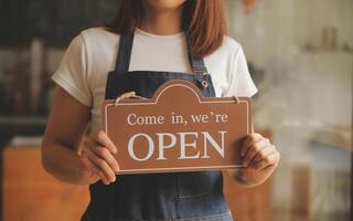 startup bem sucedido pequeno empresário sme beleza garota stand com smartphone tablet no restaurante café. retrato do proprietário do café barista mulher bronzeada asiática. conceito de negócio de vendedor de sme empreendedor foto