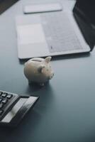 jovem ásia mulher salvando para aposentadoria salvando dinheiro através uma porquinho banco e levando notas em caderno, poupança conceito. foto