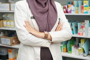 fechar acima cruzado braço do muçulmano mulheres farmacêutico vestindo hijab dentro hospital foto