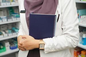 fechar acima mão trazer livro do muçulmano mulheres farmacêutico vestindo hijab dentro hospital foto