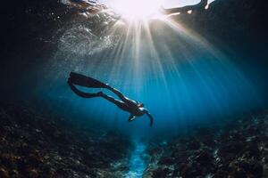 jovem mergulhador mulher com barbatanas desliza e surpreendente Sol raios. mergulho livre embaixo da agua dentro oceano foto