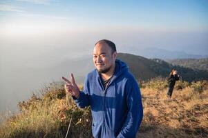 ásia gordo homem com lindo nascer do sol do khao san nok wua montanha kanchanaburi.khao san nok wua é a Altíssima montanha dentro khao Laem nacional parque. isto é 1767 metros acima mar nível. foto