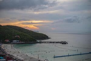 pôr do sol Visão do tawean de praia com lotado do turista em a de praia dentro nublado dia.tawaen de praia é a a Principal de praia em a popular koh Larn ilha. foto