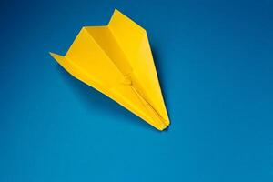 amarelo origami avião em uma azul fundo. foto