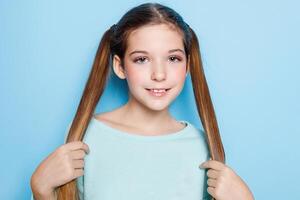 pequeno menina fazendo careta e tendo Diversão às Câmera isolado sobre azul fundo. foto