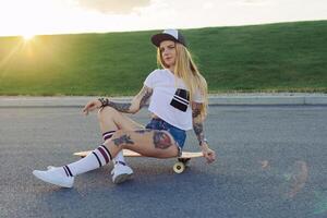 retrato do uma hipster jovem menina sorridente com uma Longboard às pôr do sol. foto