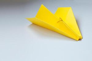 amarelo origami avião em uma branco fundo. foto