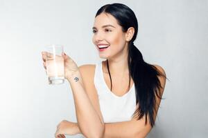 sorridente jovem mulher com vidro do água foto