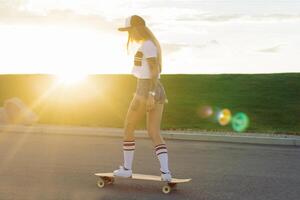 retrato do uma hipster jovem menina sorridente com uma Longboard às pôr do sol. foto