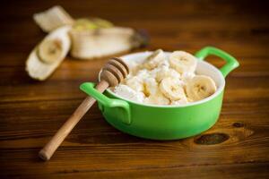 caseiro chalé queijo dentro uma tigela com bananas e querida foto