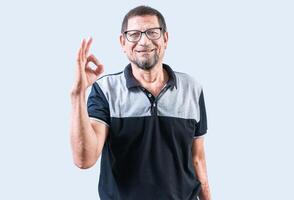 sorridente idosos homem gesticulando Está bem isolado. alegre velho homem gesticulando aprovado em branco Backgroud foto