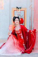 mulher vestir China Novo ano. retrato do uma mulher. pessoa dentro tradicional fantasia. mulher dentro tradicional fantasia. lindo jovem mulher dentro uma brilhante vermelho vestir e uma coroa do chinês rainha posando. foto