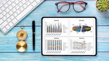 o negócio analytics conceito, uma tábua com dados gráficos descansos em uma azul de madeira mesa, complementado de uma vintage bússola, copos, e teclado, ilustrando a navegação do o negócio tendências. foto