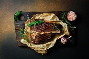 t-bone bife com alecrim em pergaminho papel. carne bife em uma Sombrio fundo. eu no. foto