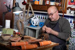 artesão trabalhando a couro dentro dele pequeno selaria oficina foto