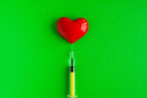 volumétrico coração forma com uma seringa em uma verde fundo. congênito coração defeito foto