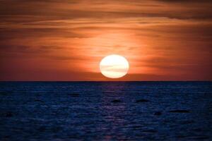pôr do sol sobre a báltico mar. a vermelho Sol afunda para dentro a mar. tarde atmosfera foto