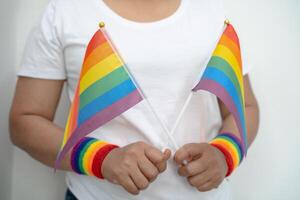 mulher segurando lgbt arco Iris colorida bandeira, símbolo do lésbica, gay, bissexual, transgênero, humano direitos, tolerância e paz. foto