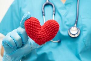 médico segurando um coração vermelho na enfermaria do hospital, conceito médico forte e saudável. foto