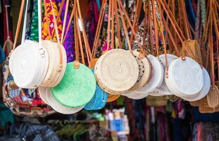 icônico rattan mão bolsas suspensão para lembrança às uma rua fazer compras dentro ubud mercado do bali ilha, Indonésia. foto