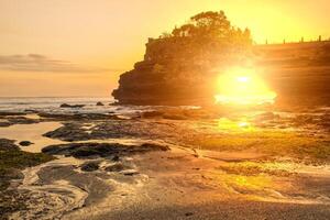 lindo pôr do sol Visão Veja através arco Rocha abaixo pura batu Bolong a icônico hinduísmo mar têmpora dentro bali ilha do Indonésia. foto