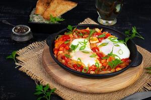 Shakshuka com grelhado pão. frito ovos com tomate, pimenta, alho e ervas foto