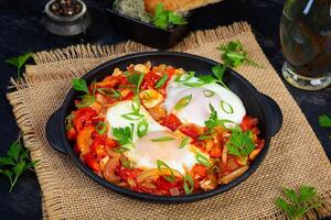Shakshuka com grelhado pão. frito ovos com tomate, pimenta, alho e ervas foto