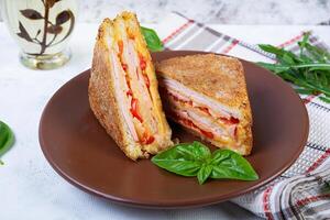 sanduíches frito dentro Migalhas de pão com presunto, queijo e tomates foto