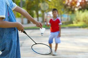 ásia menina e Garoto jogar badminton ao ar livre às a parque juntos em período de férias. suave e seletivo foco. foto