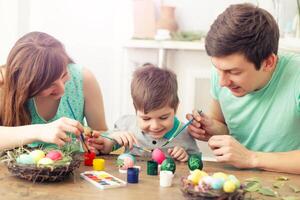mãe, pai e filho estão pintura ovos. feliz família estão preparando para Páscoa. foto